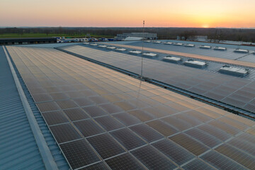 Aerial view of blue photovoltaic solar panels mounted on industrial building roof for producing green ecological electricity. Production of sustainable energy concept