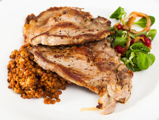 Baked pork shank with lentils garnishing with green corn salad and berries of redcurrant..