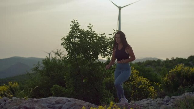 Slow motion video of a girl jogging in the mountains at sunset. A woman runs to the top of the mountain and raises her hands to the top, a happy man after playing sports and fitness in nature.