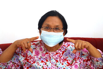 Senior elderly woman wearing face mask and pointing on it.