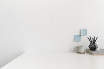Office table, empty desk with supplies and white wall copy space.	