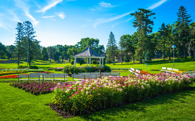 Vibrant sunrise garden landscape with a pavilion, benches, and flowers. Bright cheerful public park landscape at Tuthill Park in Sioux Falls, South Dakota. - obrazy, fototapety, plakaty