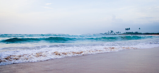 Early Morning Ocean Waves Crashing onto the Sandy Beach Under Overcast Sky