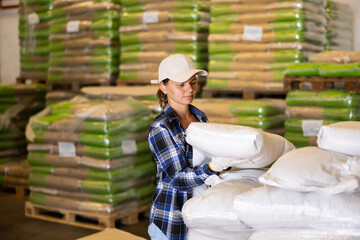 Fototapeta premium Female worker stacks bags of groceries in a large warehouse