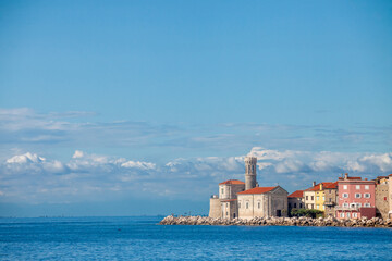 Panorama of  Piran, Slovenia, with Adriatic sea in front, with blue water and sky, on a wharf quay, during a sunny summer afternoon. Piran, or Pirano, is a slovenian city on the adriatic sea in istria - obrazy, fototapety, plakaty