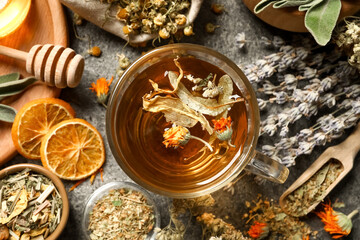 Freshly brewed tea and dried herbs on grey table, flat lay