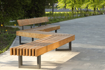 Wooden bench in city park on sunny morning - obrazy, fototapety, plakaty