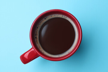Red mug of freshly brewed hot coffee on light blue background, top view