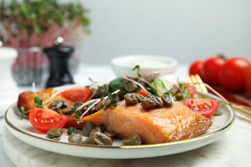 Delicious salmon with salad and capers on table, closeup