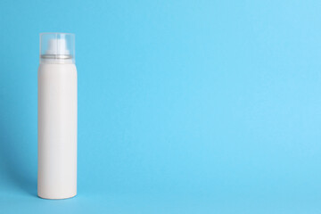 Bottle of dry shampoo on light blue background, space for text