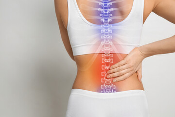 Woman suffering from pain in back on light grey background, closeup. Space for text
