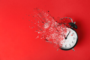 Time is running out. Black alarm clock vanishing on red background, top view