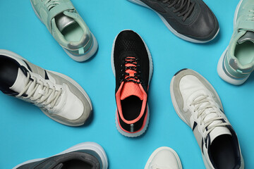 Different stylish sport shoes on light blue background, flat lay