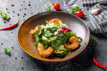 Salad with deep-fried shrimps and mix salad on grey table