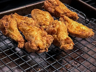 Close up, selective focus on homemade fried chicken wings on a drying rack inside a home kitchen