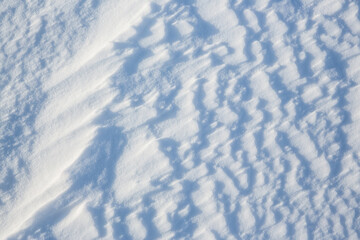 Beautiful winter background with snowy ground. Natural snow texture. Wind sculpted patterns on snow surface.