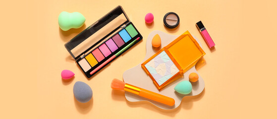 Makeup sponges, brush and decorative cosmetics on beige background, top view