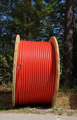Große Holztrommel, auf der ein knallrotes Kabel aufgerollt ist. Es ist über 5 Zentimeter (2 Zoll)...