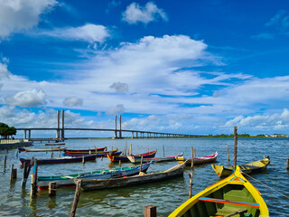 Artisanal fishing boats moored in a river with a cable-stayed bridge to the bottom - obrazy, fototapety, plakaty
