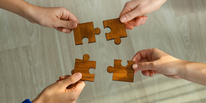 People assembling wooden puzzle, top view