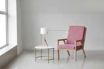 Fototapeta na wymiar Comfortable armchair with table and lamp near light wall in room