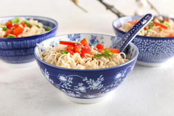 Bowl of tasty noodles on light background