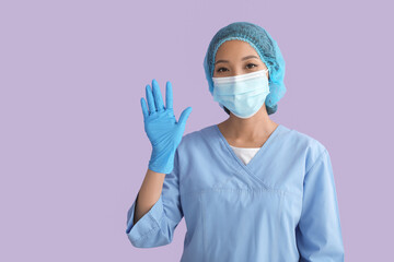Asian nurse in medical mask waving hand on color background
