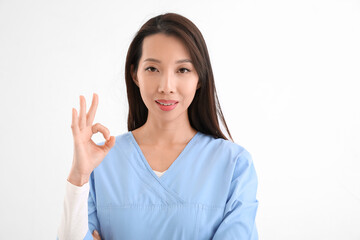 Female Asian nurse showing OK on white background
