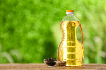 Bottle of sunflower oil and bowls with seeds on table outdoors