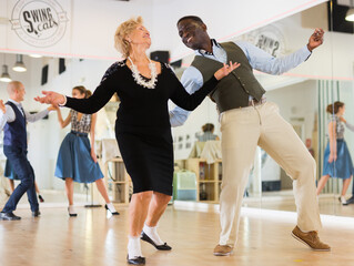 Lady learning to dance lindy hop with man in dance school