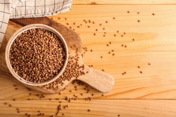 Bowl with buckwheat grains and napkin on wooden table
