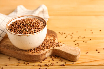 Bowl with buckwheat grains on wooden board