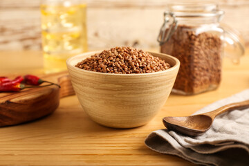 Bowl with dry buckwheat grains on wooden table