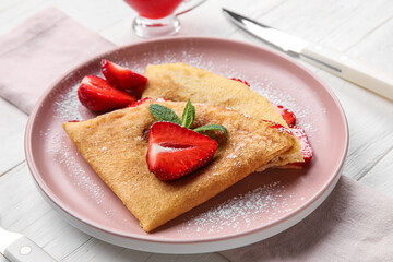 Plate of thin pancakes with strawberries and mint leaves on white wooden background, closeup