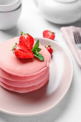 Plate of tasty pink pancakes on table, closeup