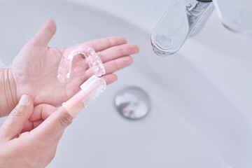 Woman's hand holding an invisible orthodontics made of silicone to clean it using a silicone finger...