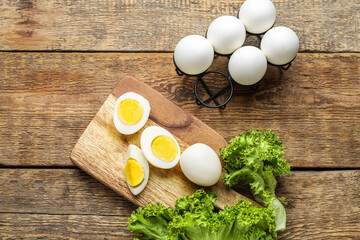 Board with boiled chicken eggs and lettuce on wooden background