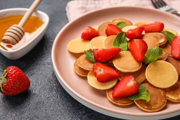 Plate with mini pancakes, strawberry and mint on table