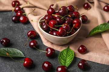 Bowl of tasty cherries with water drops on dark background