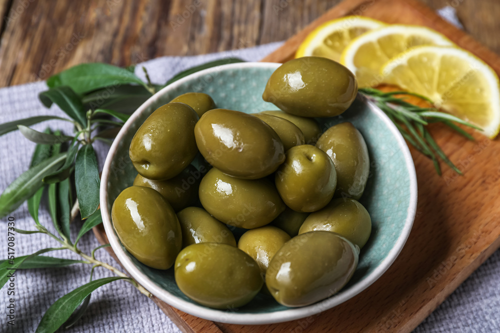 Wall mural Bowl of tasty green olives on table, closeup