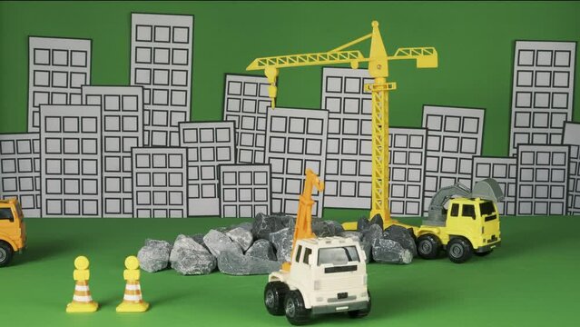 Stop-motion on green background, construction vehicles toys, trucks, backhoes, and cranes work at site, transport resource materials, rock, and mortar, real estate business, and city development.