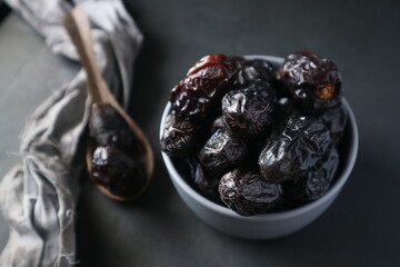Bowl of dates fruits on a dark concrete background. The view from the top.