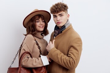 a close horizontal photo of a beautiful, stylish couple in autumn clothes. A woman stands in a hat and holds a bag on her shoulder, snuggling up to a man with a joyful smile on her face