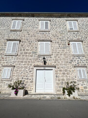 Fototapeta na wymiar Gray stone building with white shutters on the windows