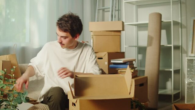 Moving to new house. Real estate, buying flat apartment. Young man wrapping things in cardboard boxes, guy owner during relocation. Property purchasing. Housing service concept.