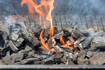 Fire is blazing on the BBQ grill over flaming hot charcoal for cooks the food