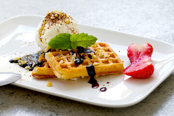 ice cream with Belgian waffles, strawberries, fresh mint, chocolate topping and nuts