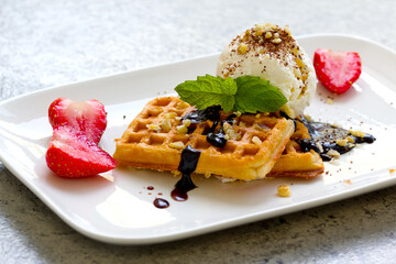 ice cream with Belgian waffles, strawberries, fresh mint, chocolate topping and nuts