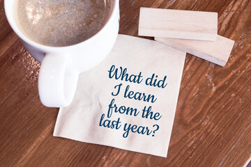 What did I learn from the last year? Handwriting on a napkin with a cup of espresso coffee
