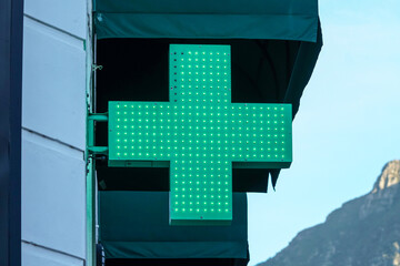 green cross illuminated led sign or signage indicating a pharmacy, dispensary or a chemist concept health and medical - obrazy, fototapety, plakaty